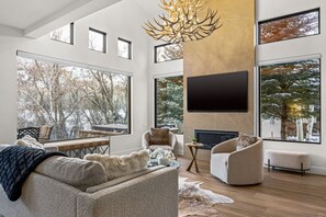 Sophisticated, open floor plan living area with fireplace, smart TV, and vaulted ceilings