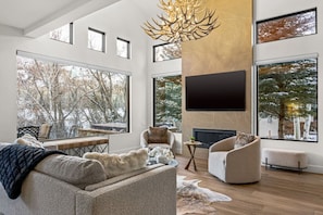 Sophisticated, open floor plan living area with fireplace, smart TV, and vaulted ceilings