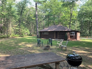 OVERALL: The backyard at the cabin showing the fire pit, picnic table, and charcoal grill