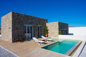 Private pool framed by traditional stonework and sunlit swimming pool area.