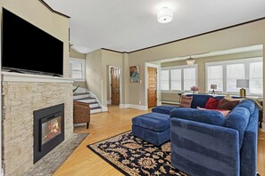 Natural light pours in through wide windows, enhancing the spacious feel of this comfortable short-term rental. Enjoy thoughtful decor, hardwood floors, and easy access to the kitchen and dining area.