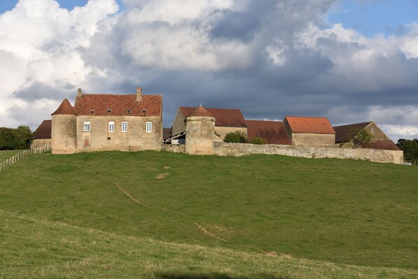 Le gîte se trouve derrière le logis principal. Jardin-terrasse sur la droite.