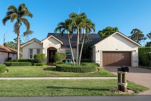 Street view of Villa Piloto with lush lawn & serene palm-lined surroundings