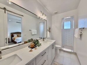 The ensuite bathroom in the primary bedroom upstairs offers a beautifully tiled shower and a double vanity
