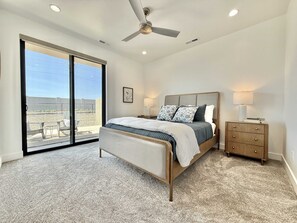 The primary suite on the main level features a queen sized bed, an ensuite bathroom with a beautifully tiled shower, and private patio access