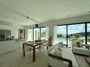 Villa features an open-concept living space that seamlessly blends the living room, dining area, and kitchen, creating bright and airy atmosphere perfect for relaxation and entertaining, all while offering stunning views of the surrounding landscape.