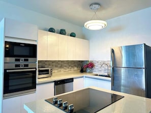 The apartment boasts a modern kitchen equipped with sleek appliances, a spacious island, and chairs—perfect for casual dining or sharing conversations while cooking.