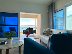 The apartment features a stylish living room designed for relaxation and comfort, with tasteful decor and a cozy ambiance that complements the serene oceanfront setting.