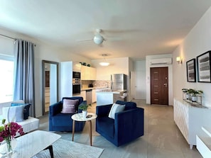 The apartment features an open-concept living space, seamlessly blending the living room, dining area, and kitchen into one airy, spacious area, perfect for relaxation and socializing.