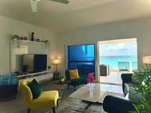 The apartment features a stylish living room designed for relaxation and comfort, with tasteful decor and a cozy ambiance that complements the serene oceanfront setting.