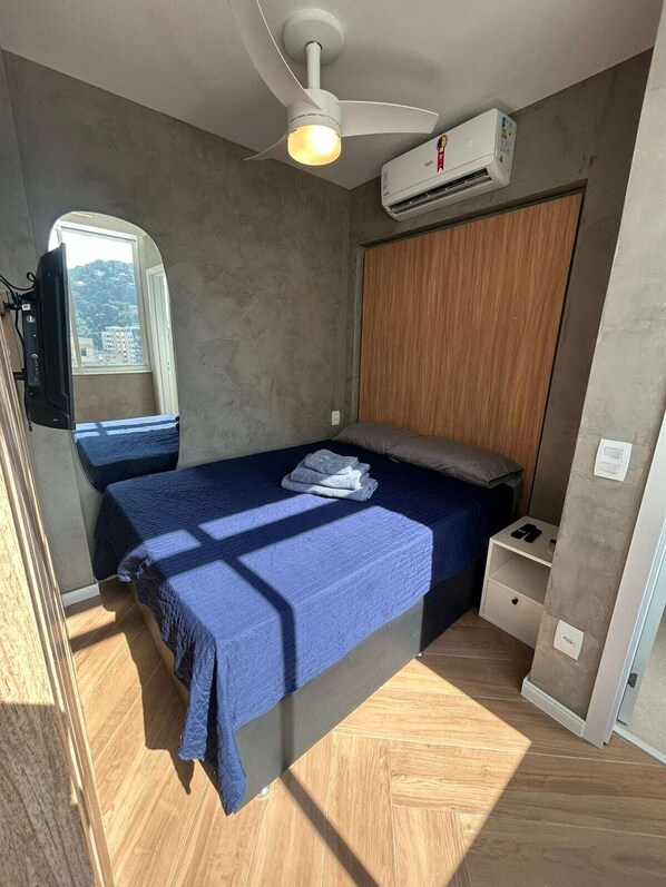 Accent lighting behind the bed, ceiling fan, new A/C, night stand for storage, and luggage storage beneath the bed.