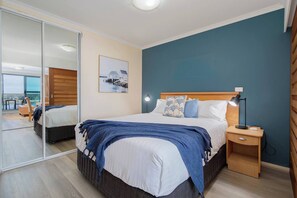 Rest easy in the queen bed framed by a soft blue feature wall and mirrored wardrobe, offering both style and storage in a private sleeping zone.