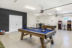The garage game room offers a pool table, foosball table/ping pong, an arcade, and a TV.