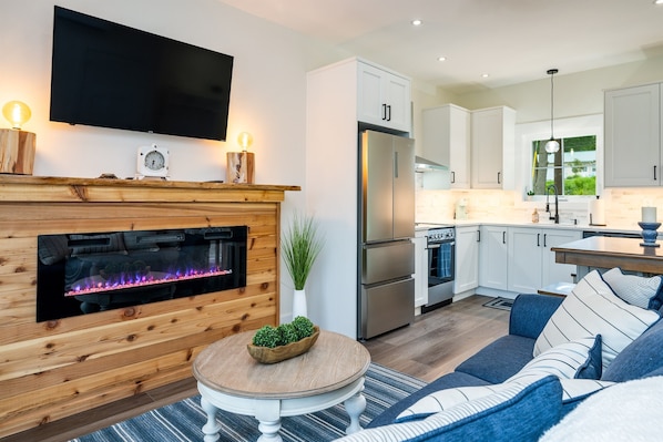 Cozy up in this inviting living area featuring a modern electric fireplace, smart TV, and seamless flow into the kitchen.