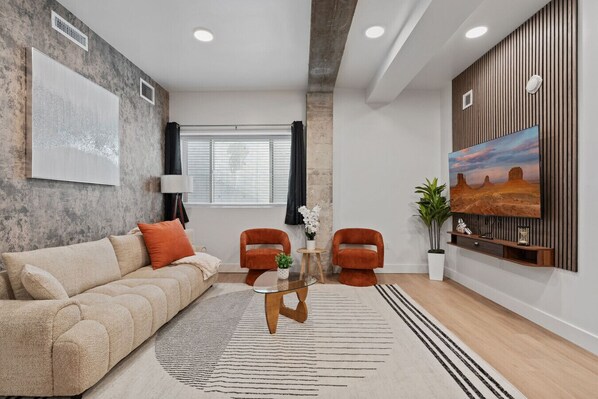 Kick back in a stylish living room featuring a large TV, lush plant accents, and soft lighting.