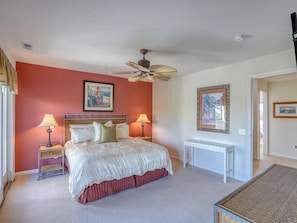 This cozy second bedroom showcases a comfortable king-sized bed with decorative pillows, tasteful artwork, and ample natural light streaming through sliding doors that lead to a private deck.