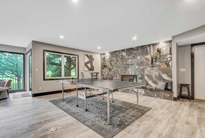 Stylish rec space with a stone accent wall, fireplace, and ping pong table—perfect for indoor fun and group hangouts..