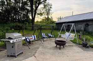 Backyard patio with swings and BBQ grill for relaxing days in the countryside.