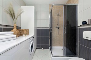 The bathroom's contemporary design includes fresh towels and a hairdryer.