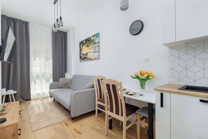 A brighter view of the living room with dining table and gray sofa.