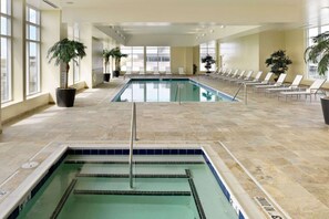 Indoor pool and hot tub with lounge chairs and palm plants