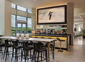Lobby bar with tall seating, artwork, and bright city views