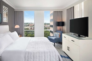 Guest room with king bed, TV, and river view from large windows