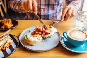 Breakfast plate with eggs, ham, coffee, and pastries on table