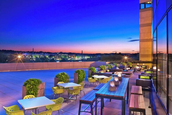 Rooftop patio with city views, fire pits, and evening lighting