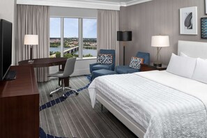 Room with king bed, desk, and window overlooking river and bridge