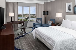 Room with king bed, desk, and window overlooking river and bridge