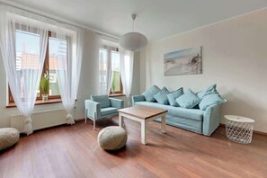 Another angle of the living room showcasing the stylish arrangement of furniture. Light blue hues in the decor complement the natural tones of the hardwood floor, creating a serene atmosphere.