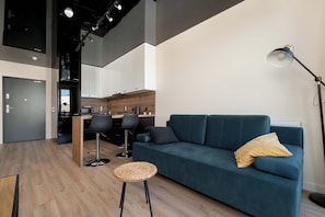 A modern open-plan living space with a cozy sofa, industrial-style lighting, and a small dining area.