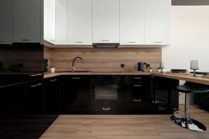 A sleek black-and-wood kitchen with built-in appliances and minimalist cabinetry.