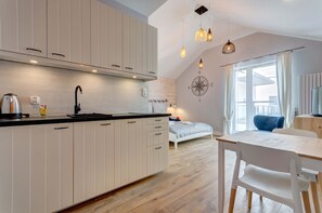 A modern kitchenette with sleek white cabinets, wooden countertops, and a dining area perfect for meals or work.