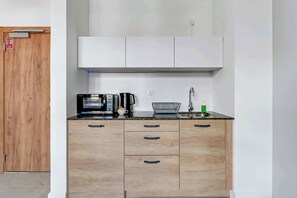 A modern kitchenette with white cabinetry, wooden countertops, and appliances neatly integrated into the design.