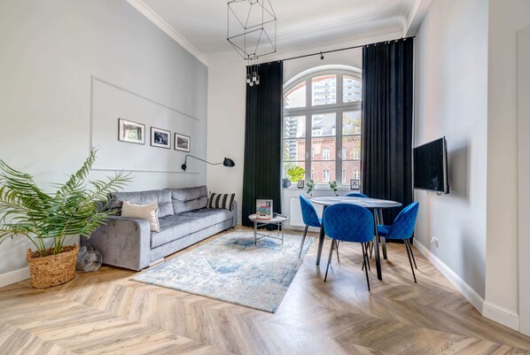 A bright and modern living room with a round dining table, elegant blue chairs, and a plant adding a fresh touch to the decor.