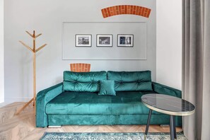 A cozy space featuring a teal sofa, framed artwork, and large windows letting in natural light.