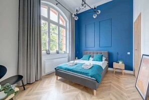 A stylish bedroom with a headboard, white bedding, and a minimalist aesthetic that emphasizes comfort.