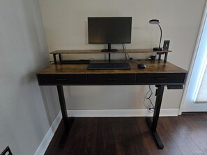 Ergonomic sit/stand desk with monitor, keyboard, mouse and docking station.