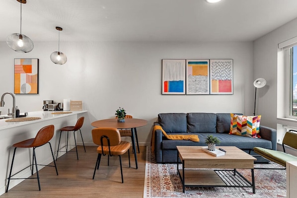 Vibrant living and dining area with cozy seating, modern art, and bar-height breakfast counter