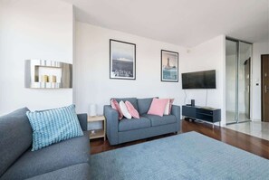 A comfortable and inviting corner in the living room, featuring soft pillows and a flat-screen TV for entertainment.