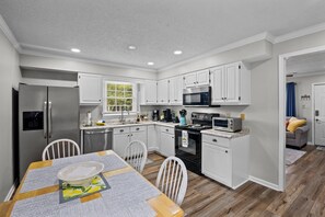 Modern kitchen with stainless steel appliances, coffee makers & utensils.