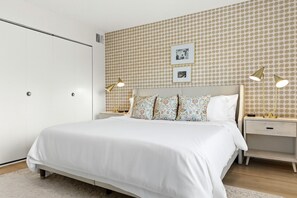 Inviting king bedroom with patterned accent wall, bedside lighting, and soft, neutral tones.