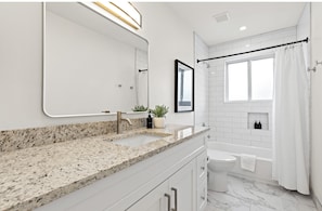 Freshly renovated bathroom with shower/tub combo and clean, modern finishes.