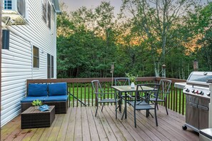 Spacious deck with dining table, BBQ grill, and comfy seating for outdoor meals and relaxation.