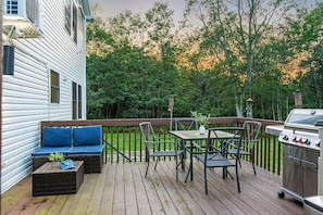 Spacious deck with dining table, BBQ grill, and comfy seating for outdoor meals and relaxation.