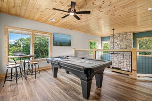 A game room with a pool table, arcade system, board games and boss toss!