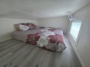 King bed in the loft with a fan and natural light. Great view of the projector screen!