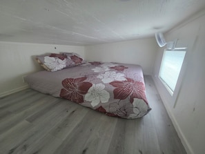King bed in the loft with a fan and natural light. Great view of the projector screen!